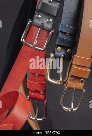 Various leather belts with metal buckles close-up on dark grey background Stock Photo