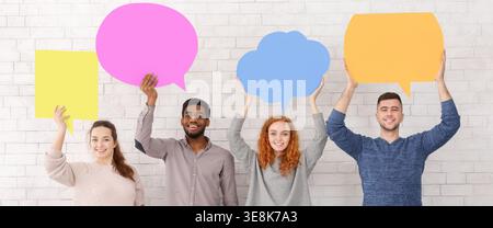 Group of People Holding Colorful Speech Bubbles on a White Wall During a Creative Activity Session Stock Photo