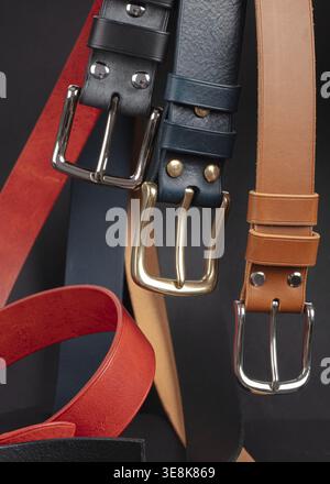 Various leather belts with metal buckles close-up on dark grey background Stock Photo