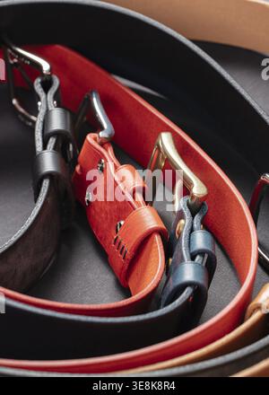 Various leather belts with metal buckles close-up on dark grey background Stock Photo