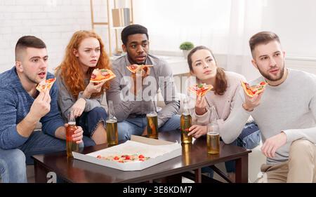 Group of Friends Enjoying Pizza and Drinks While Watching a Movie at Home During a Relaxing Evening Stock Photo