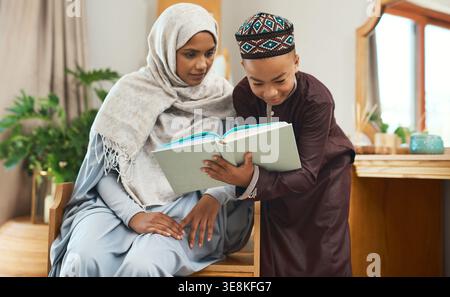 Quran, reading and muslim mother with child in home studying religion for spiritual wellness together. Arabic, support and islamic mom with boy kid Stock Photo