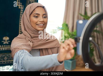 Cellphone, influencer and muslim woman in house for recording video on religion, Quran or spiritual growth. Light, phone and islamic female content Stock Photo