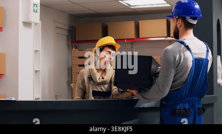 Female employee scanning barcodes on goods for stock logistics, using scanner to check product before shipping and inventory work. Person planning order distribution in storage room. Handheld shot. Stock Photo
