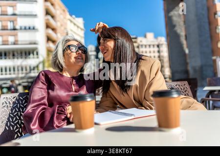 Women friends enjoying coffee and conversation outdoors in city Stock Photo