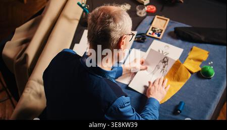 Senior tailor choosing fabric and comparing sketches, using modern clothing designs to create fashion items. Experienced couturier using tailoring equipment for needlework. Handheld shot. Stock Photo