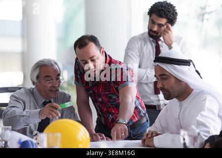 Business team discussing construction plans in a collaborative meeting with multicultural professionals Stock Photo
