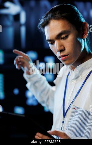 Tech support worker between server cabinets electronics providing processing resources for companies worldwide. Competent developer fixes facility supercomputers used for storing large databases Stock Photo