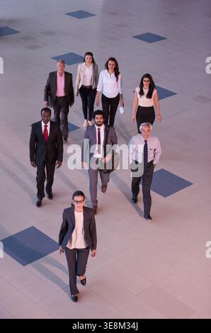 Business professionals walking together through atrium corridor, confident diverse corporate team heading to meeting Stock Photo