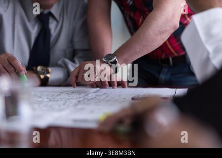 Team of professionals discussing architectural blueprints during a collaborative business meeting at a table Stock Photo