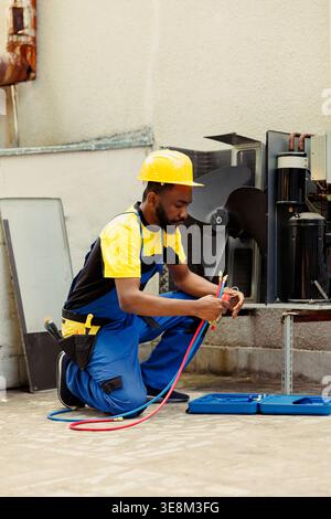 Knowleadgeable engineer doing annual hvac system maintenance, assembling manometers before starting work. Certified technician getting pressure checking tool ready for air conditioner freon tank Stock Photo