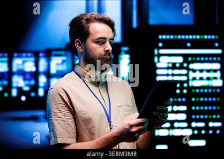 Qualified expert doing annual system review, checking data on tablet of needed server mendings. Clusters housing developed storage infrastructure supporting critical IT workloads Stock Photo