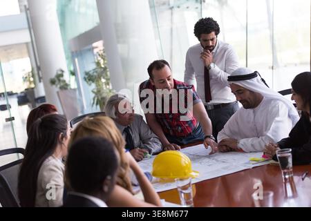 Business meeting with multicultural team reviewing blueprints and planning a construction project Stock Photo