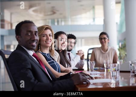 Business team meeting in modern boardroom with diverse smiling colleagues collaborating around table Stock Photo