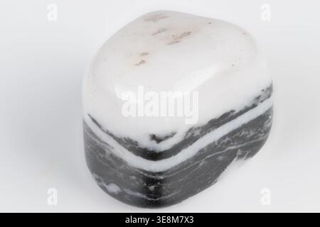 White and black striped stone closeup, polished siliceous argillite sample on white background, smooth surface, clear banding and mineral texture, stu Stock Photo