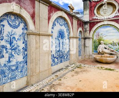 Traditional blue and white Portuguese azulejos tiles  wall featuring classical scenes  statue in courtyard Pink rococo palace of Estoi in the Algarve Stock Photo