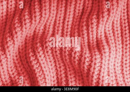Close up, macro of crumpled red knitted fabric with visible wrinkles, folds and soft waves. Soft wool texture with detailed stitches and creases, natu Stock Photo