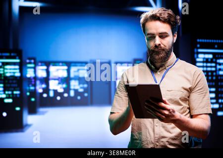 Manager in data center walking through server racks used for computationally intensive tasks such as quantum mechanics or weather forecasting. Specialist running annual equipment diagnosis Stock Photo