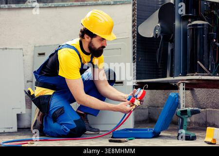 Certified repairman doing annual hvac system maintenance, assembling manifold gauges before starting work. Experienced technician checking for freon leaks leading to reduced cooling efficiency Stock Photo
