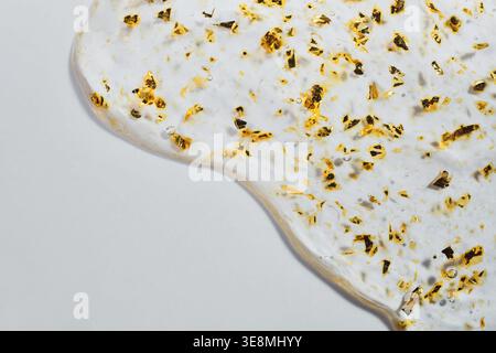 Clear cosmetic gel with shimmering gold flakes creating luxurious skincare texture Stock Photo