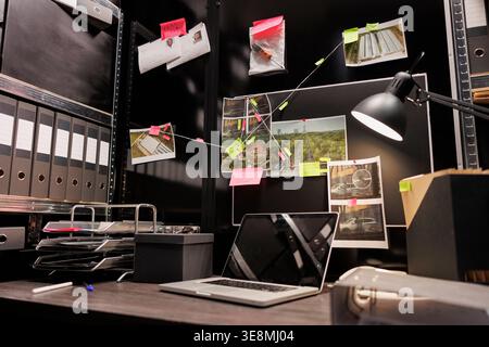 Empty dark police detective room with murder case investigation process on board. Suspect photographs connected with clues hanging on wall and file folders on racks in investigator agency office Stock Photo