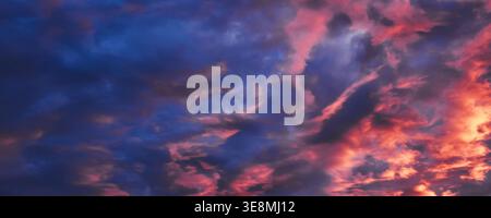 Dynamic cumulus clouds illuminated by setting sun creating vibrant evening atmosphere Stock Photo