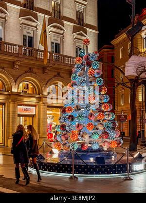 Two woman walking towards The Fendi store, past the Christmas Tree in Largo Carlo Goldoni,a small square in Rome,Italy Stock Photo