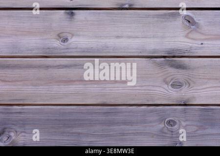 Close-up view of horizontal wooden boards showing natural wood grain patterns and circular knots, suggesting a weathered or aged surface Stock Photo