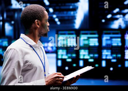 System admin checking energy efficient supercomputers hub using renewable sources to minimize consumption and reduce company carbon footprint. Proficient expert working in sustainable data center Stock Photo