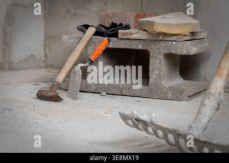 Various masonry tools and building materials are arranged on concrete blocks, suggesting an active construction or renovation project in progress Stock Photo