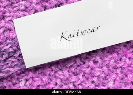 Clothes label text Knitwear over purple wool knit background closeup Stock Photo