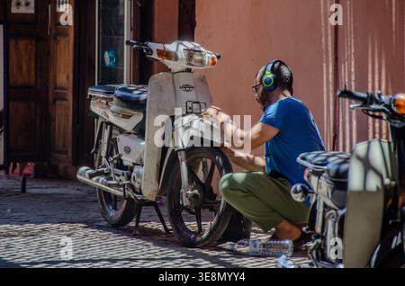 Two local women walking through a narrow street under a stone arch in Marrakesh, Morocco Stock Photo