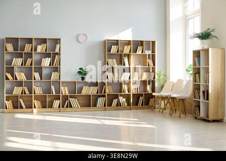 Bright library room with wooden bookshelves, chairs and natural sunlight interior Stock Photo