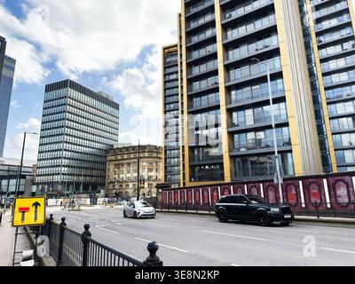 Manchester, UK - February 22, 2026: Contemporary apartment tower and office blocks in Manchester, UK with cars on a wide urban street. Stock Photo