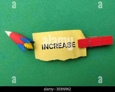 The word INCREASE written on a torn yellow piece of paper. Stock Photo