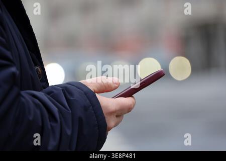 Smartphone in male hands, man using mobile phone on city street at spring Stock Photo