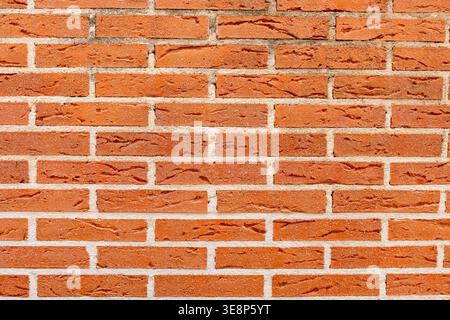 Textura de pared de ladrillos rojos rústicos con juntas de cemento blanco. Stock Photo