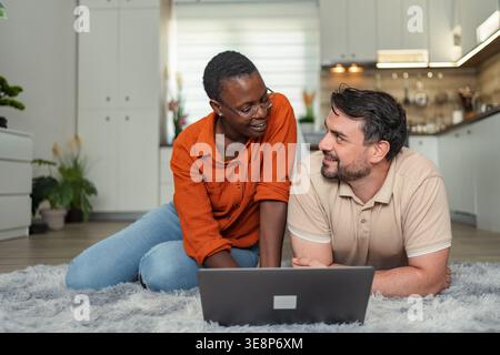 Couple relaxing on carpet using laptop at home Stock Photo