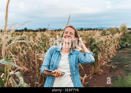 Farmer smiling and holding tablet in corn field Stock Photo