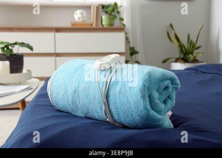 Folded electric heating pad on bed in room Stock Photo