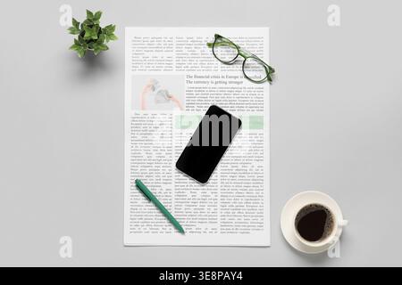 Newspaper with glasses, cup of coffee, plant and mobile phone on grey background Stock Photo