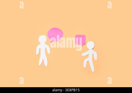Paper human figures and blank speech bubbles on color background Stock Photo