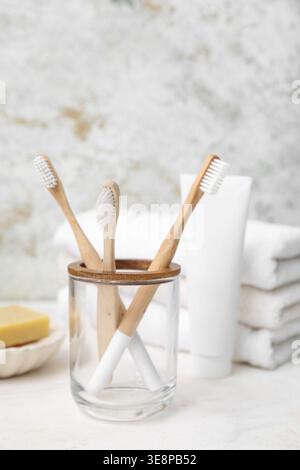 Holder with bamboo toothbrushes, paste and clean towels on light background Stock Photo