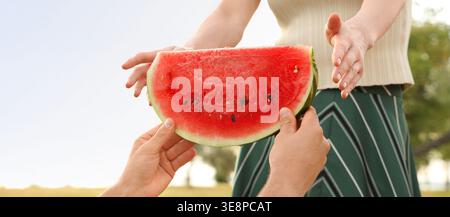 Young couple with watermelon at picnic in park, closeup Stock Photo