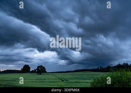 Dramatic storm clouds over green field Stock Photo