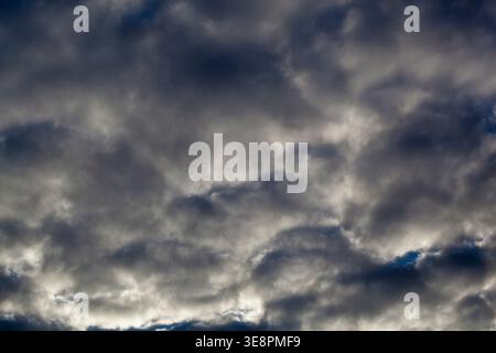 Dark clouds fill the sky above the city as an approaching storm brings ominous weather in the late afternoon. The atmosphere feels heavy and charged w Stock Photo
