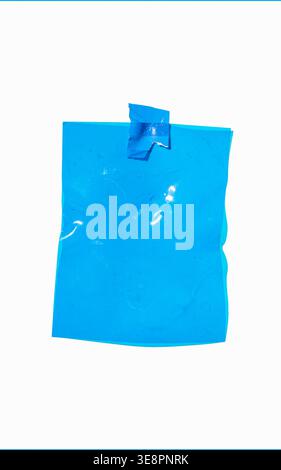Blank blue crumpled plastic film sheet attached to a white background with tape, providing copy space Stock Photo