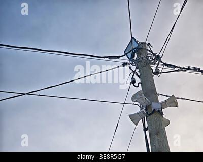 Utility pole stands tall with power lines connected, distributing electricity to homes in the area under the open sky. Stock Photo