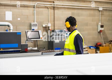 African worker operating machinery in lumberyard factory Stock Photo