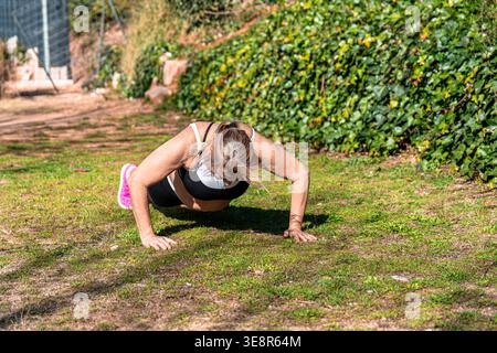 Senior woman doing outdoor fitness pushups in park Stock Photo